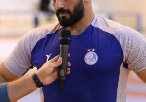 حسن یزدانی با پیراهن آبی روی تشک کشتی می‌رود